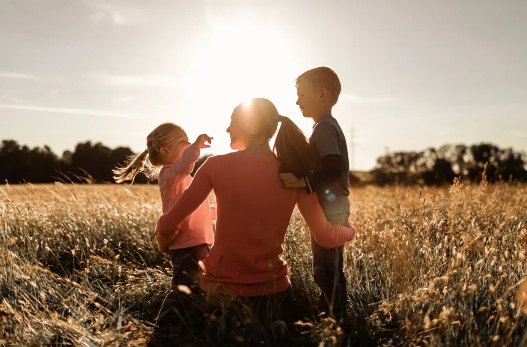 Mom with two children in a wheat field, at sunset.