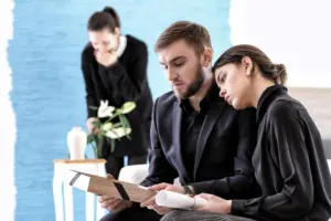 A woman laying her head on a man's shoulder wearing black and grieving.