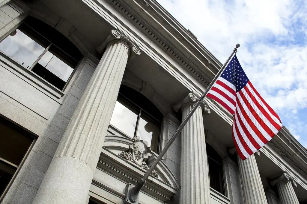 A United States flag waving over a government building.