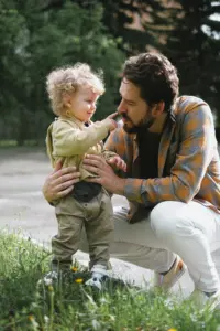 Dad kneeling next to his son talking to him.