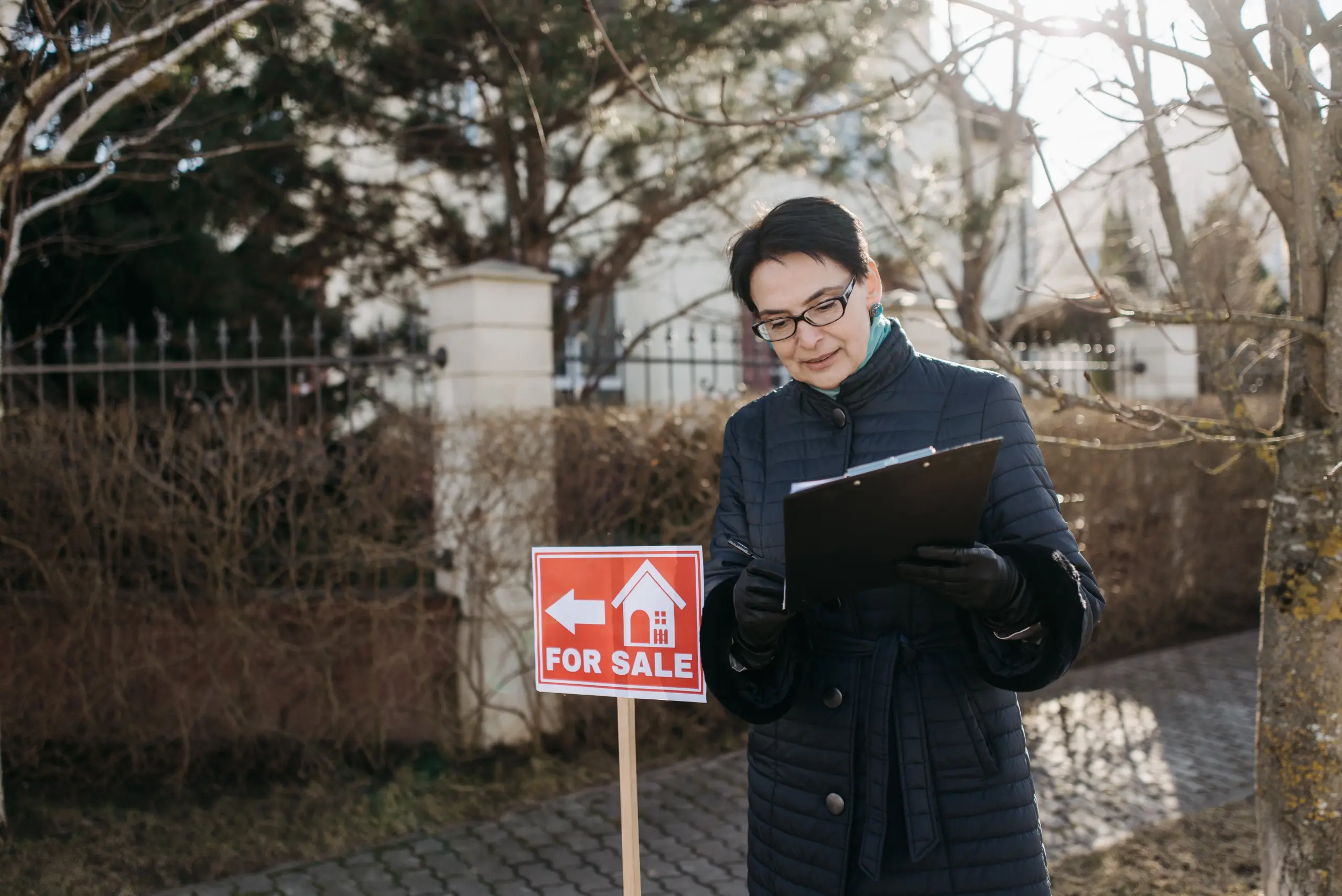 real estate agent standing by for sale sign