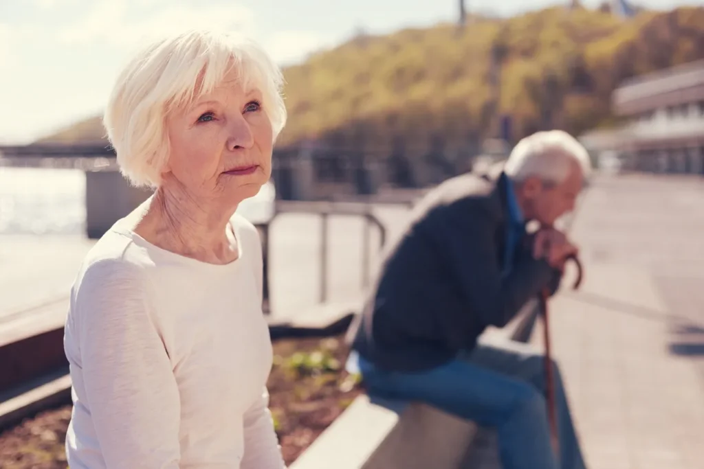 An elderly couple sitting along a path.