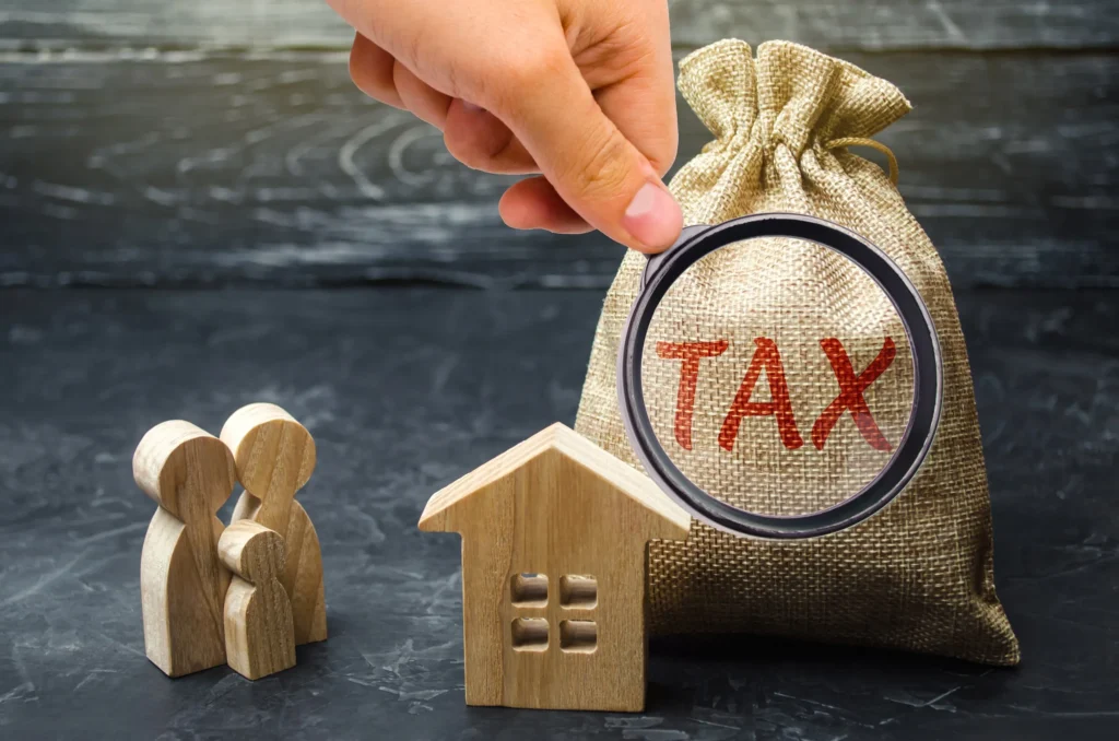 A bag with tax written on it next to a toy house.
