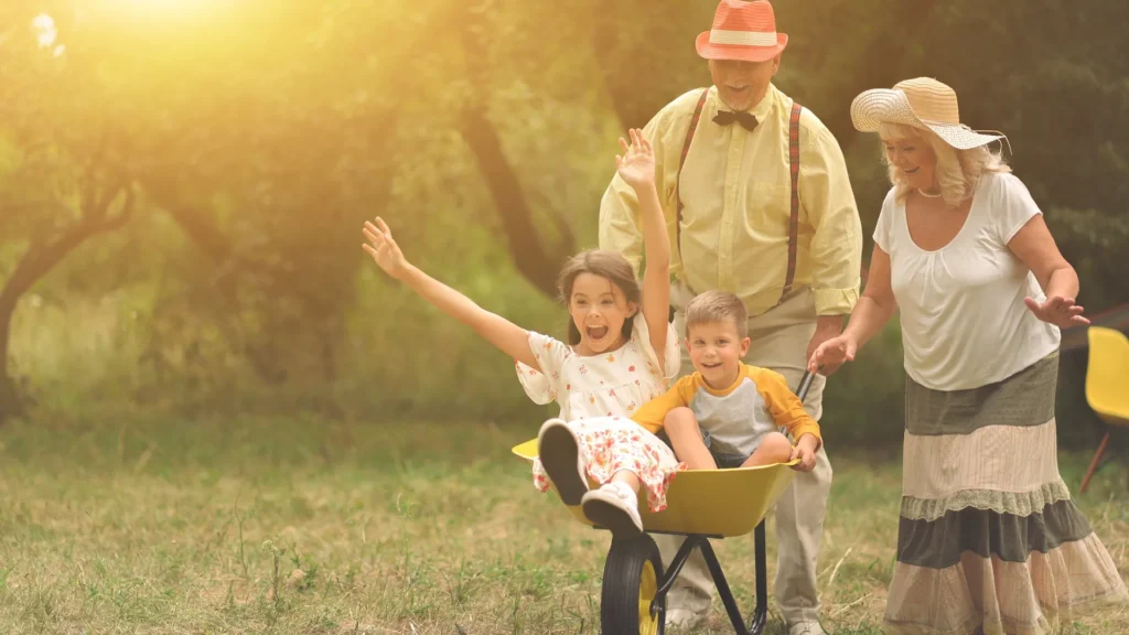 grandparents rolling grandchildren in a wheelbarrow.