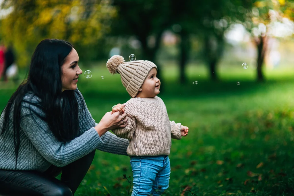 A mom walking a small child in a park.